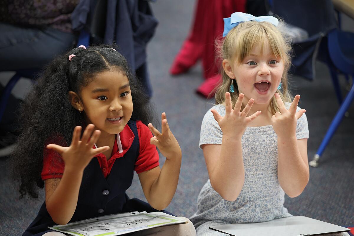 Two children make hand motions while speaking.