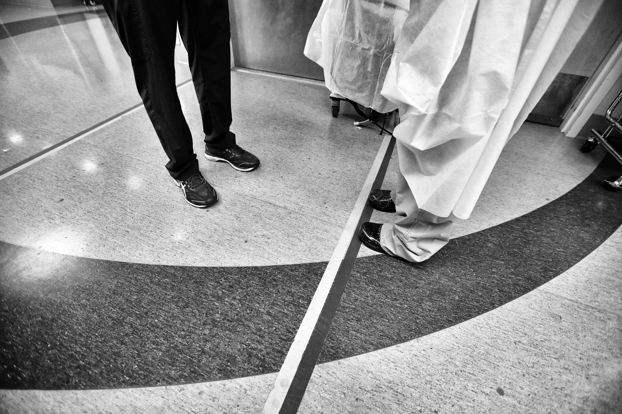 Two people standing at opposite sides of tape on the floor