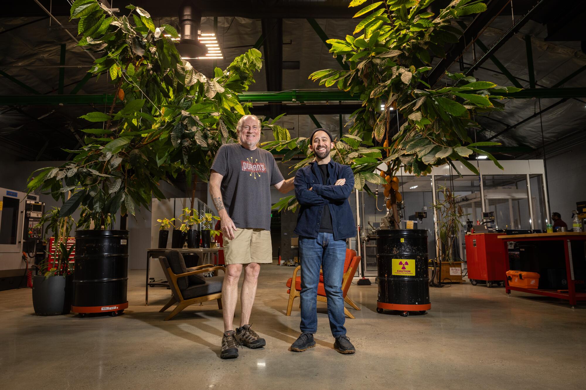 Two casually dressed men in a lab with cacao trees.
