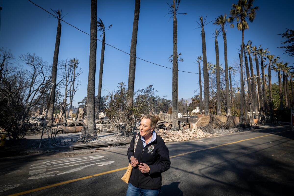 Kathryn Barger walks in front of a fire-ravaged landscape