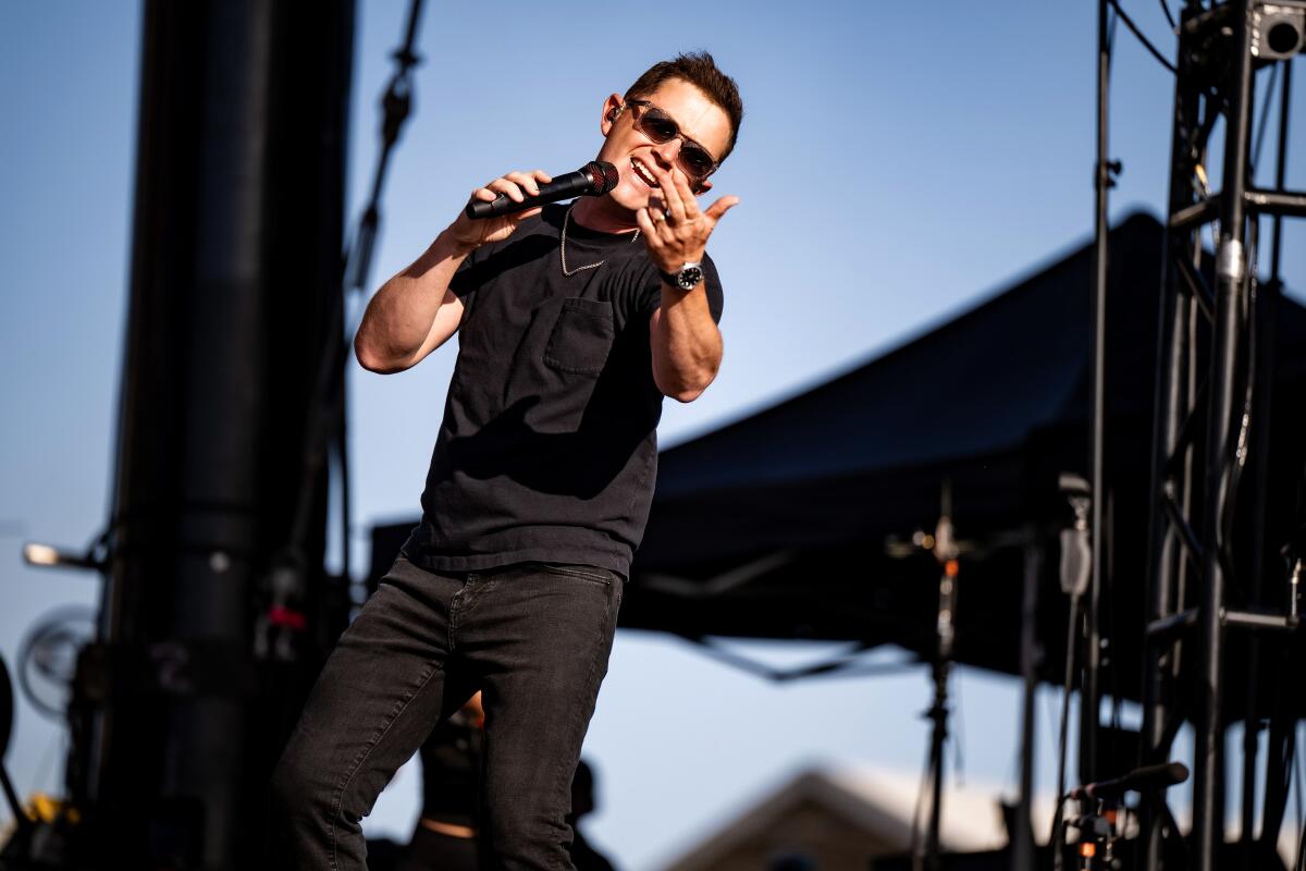 Scotty McCreery, in a black T-shirt, jeans and sunglass, sings onstage.
