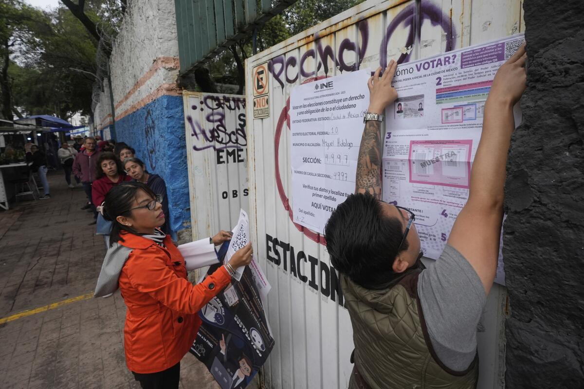 Electoral workers fix signs at a polling station Sunday in Mexico City during the country's first judicial elections.