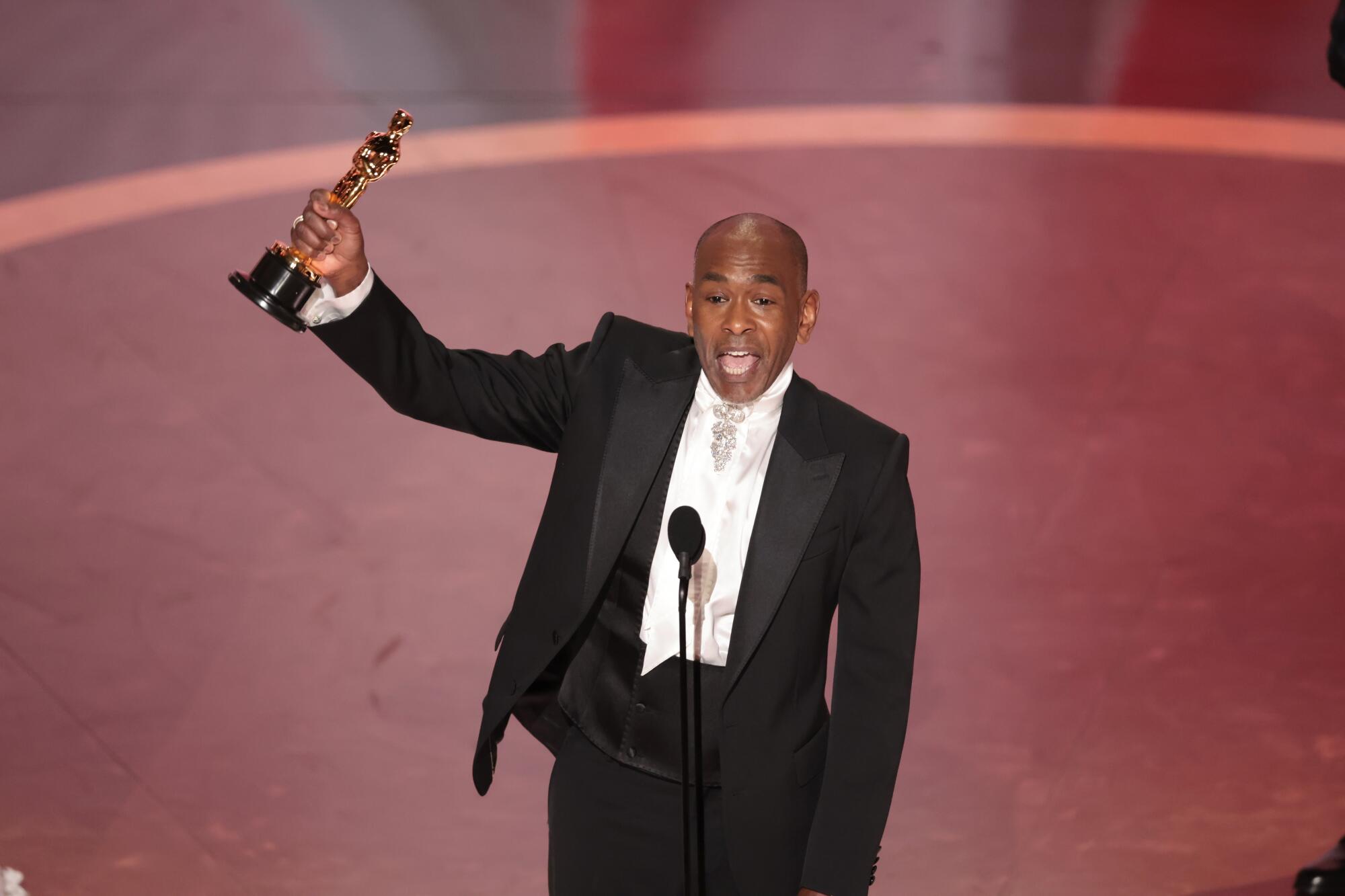 Paul Tazewell holds an oscar in his right hand.