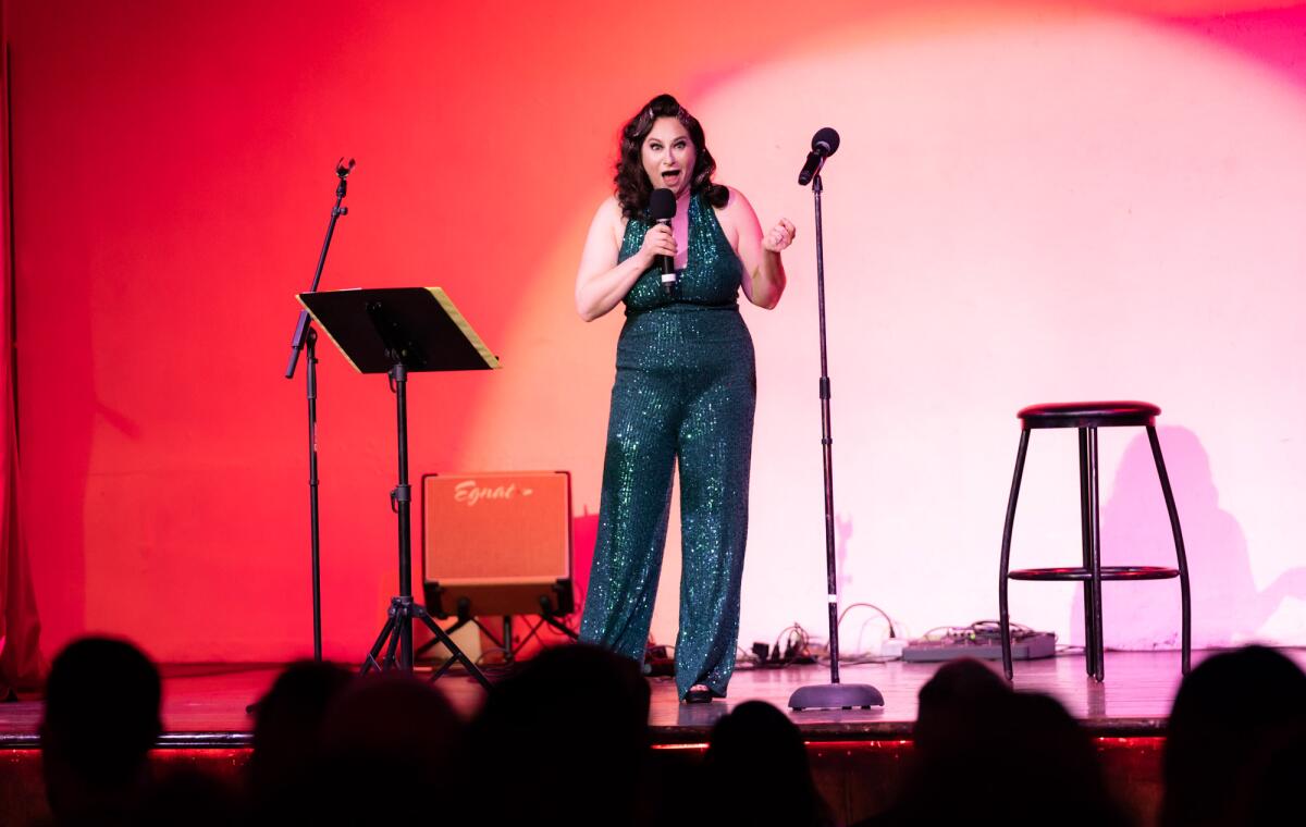 A woman speaks into a microphone onstage.