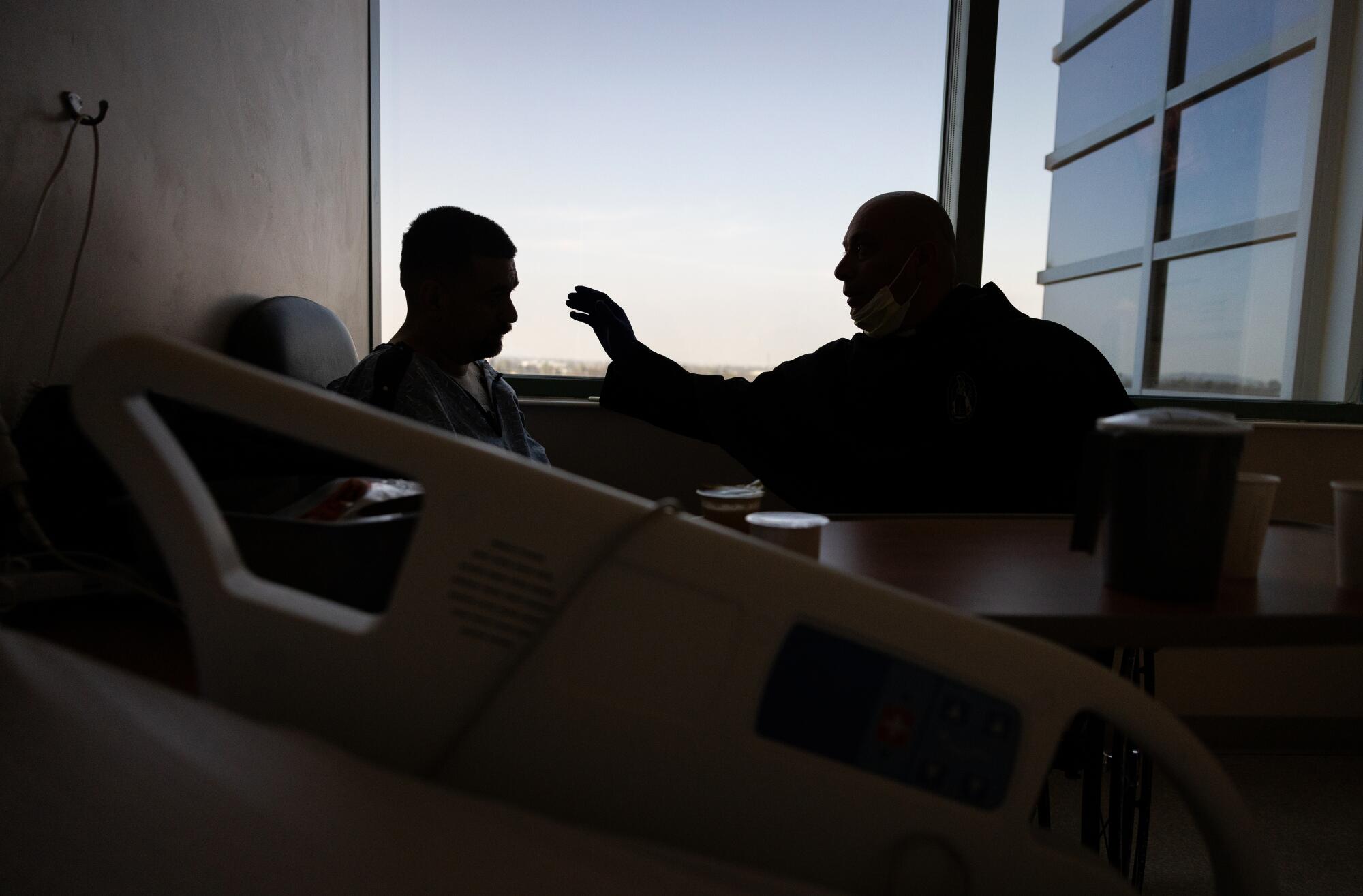 Father Cesar Galan, right, says a prayer for patient Adrian Zepeda.