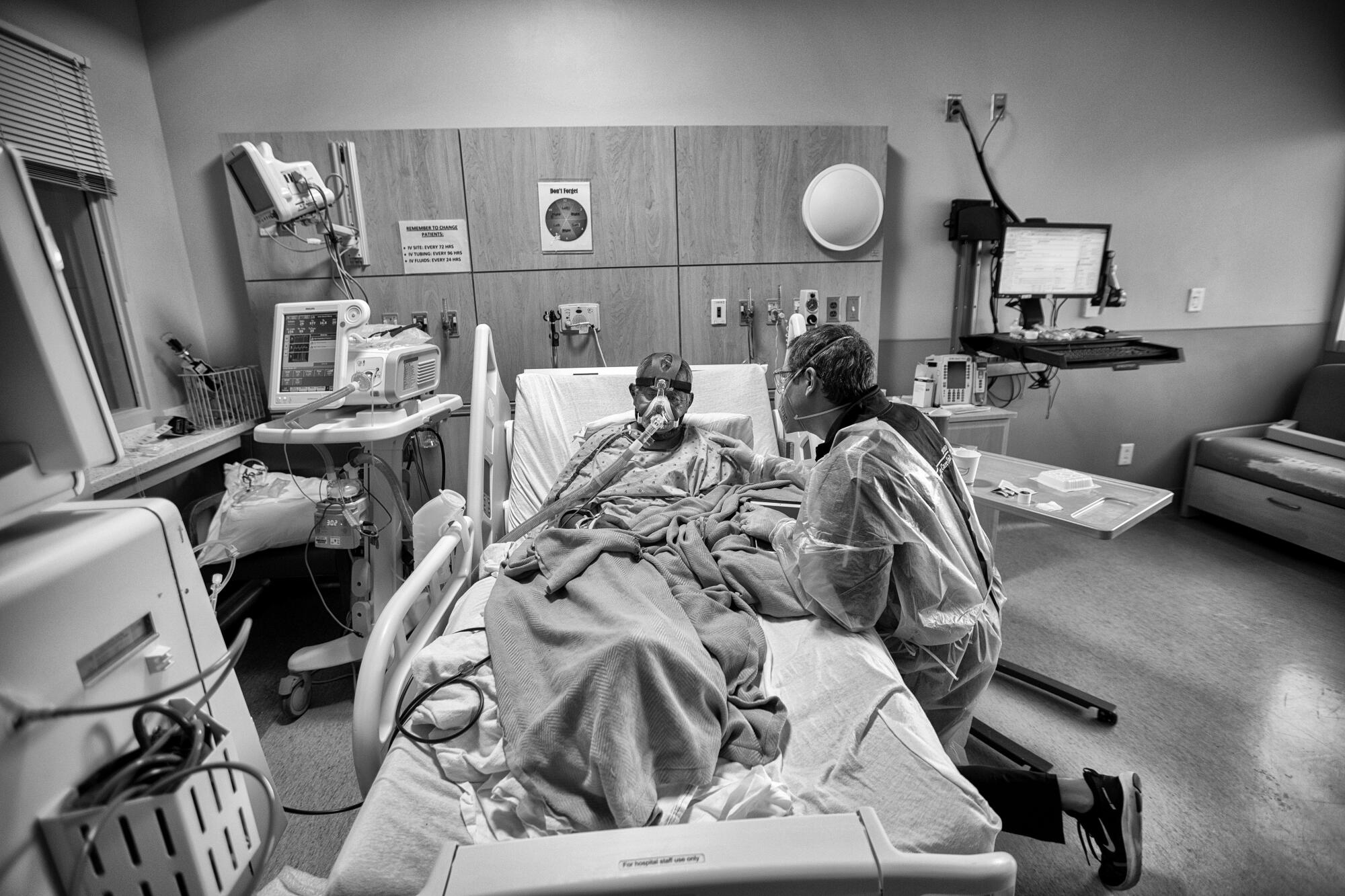 Chaplain Kevin right, kneels beside a hospital patient