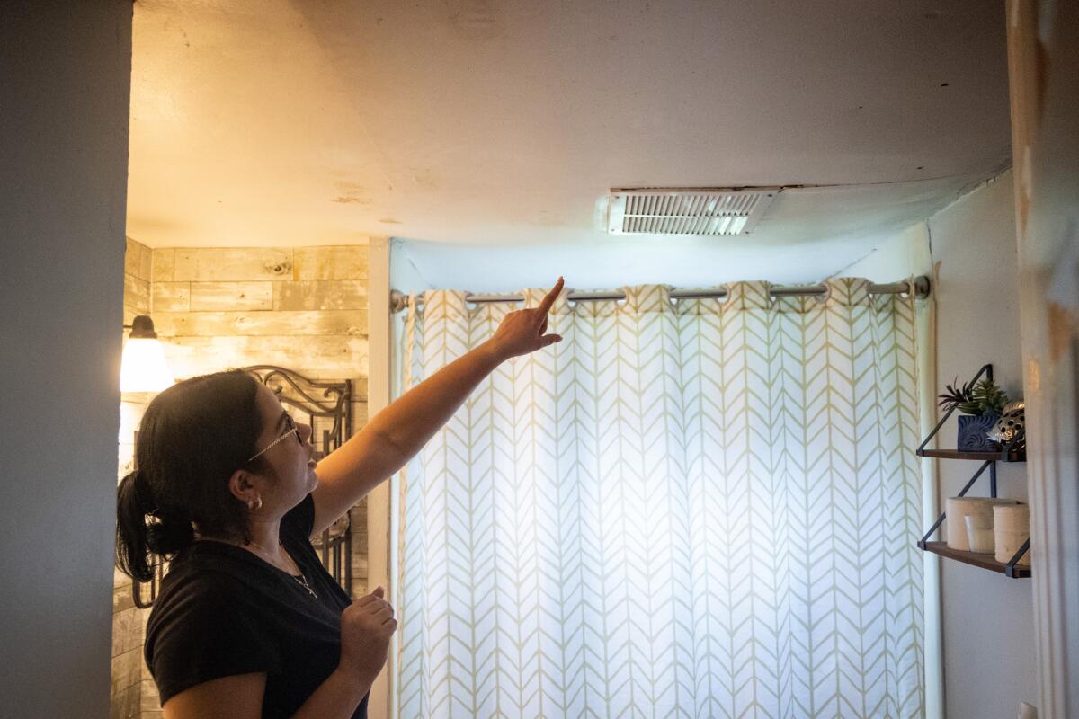 In the bathroom of her trailer, Jessica Rios Rodriguez points out the sagging ceiling caused by water damage from the fire.