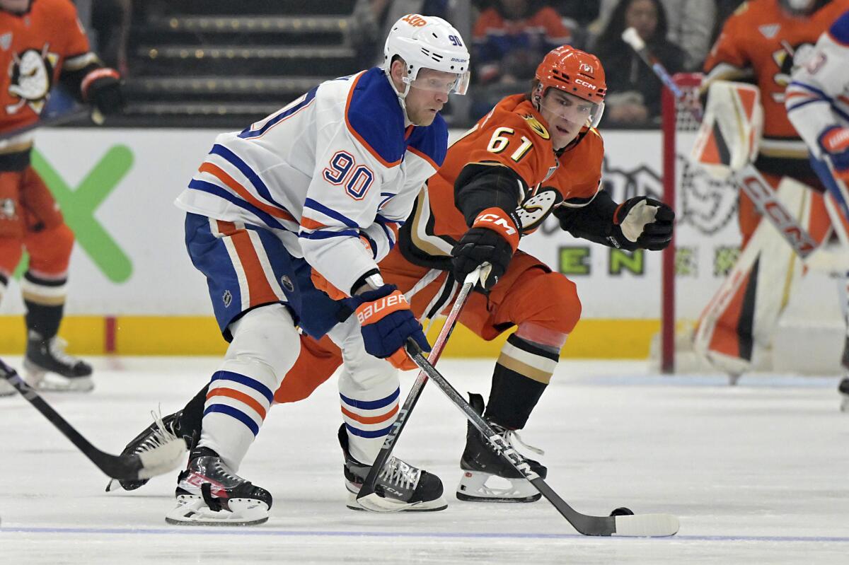 Edmonton Oilers forward Corey Perry, left, controls the puck in front of Ducks forward Cutter Gauthier.