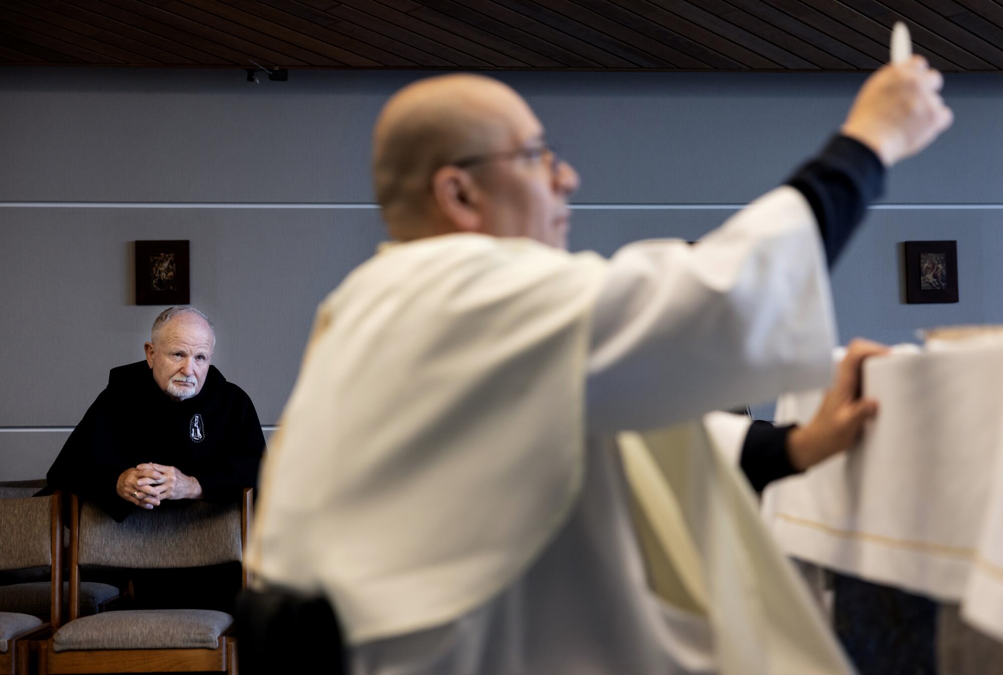 Brother Richard Hirbe, left, attends a Mass conducted by Father Cesar Galan, right, at St. Francis Medical Center in Lynwood.