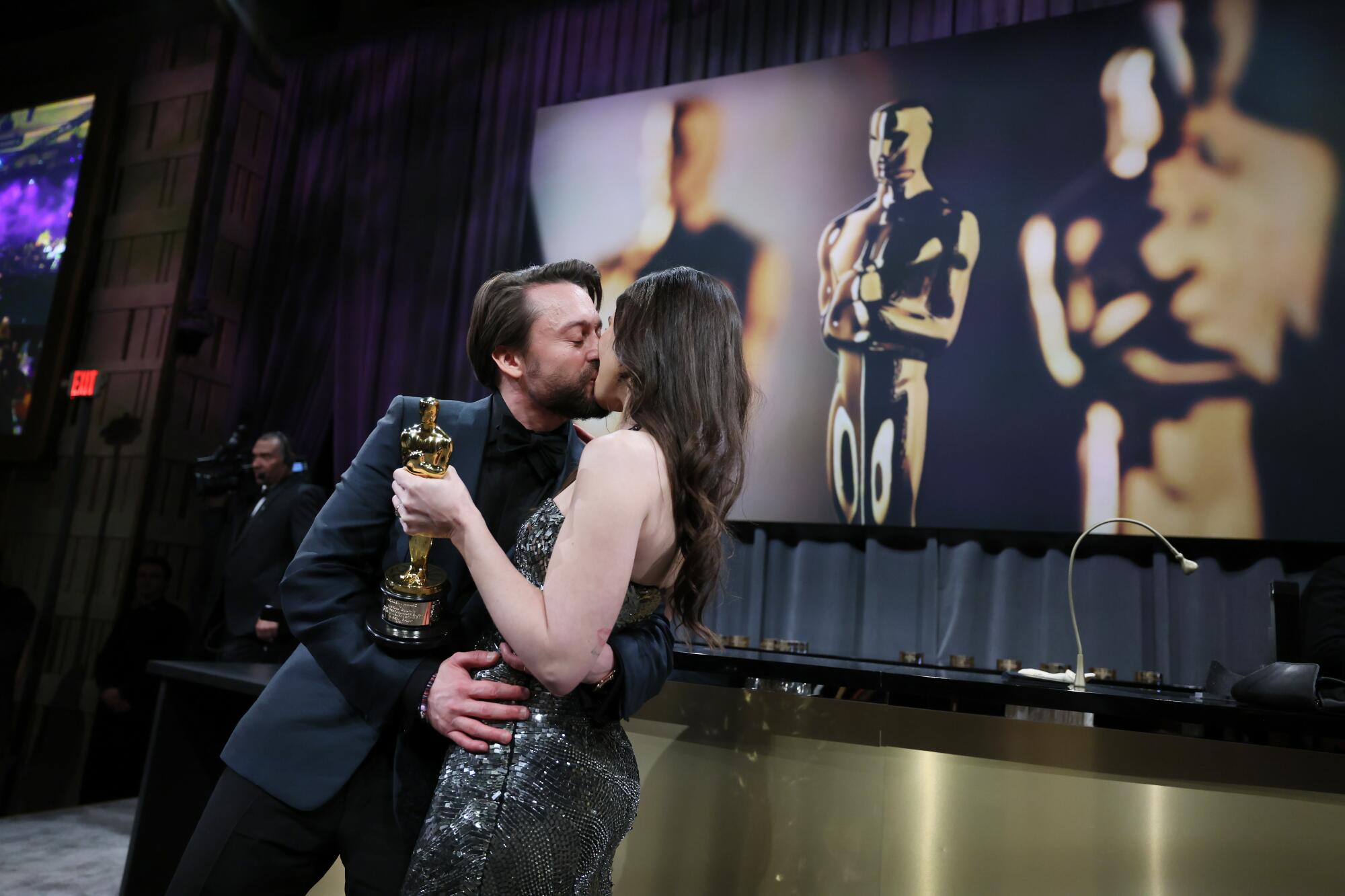 Kieran Culkin kisses his wife, Jazz Charton, as she holds his Oscar.