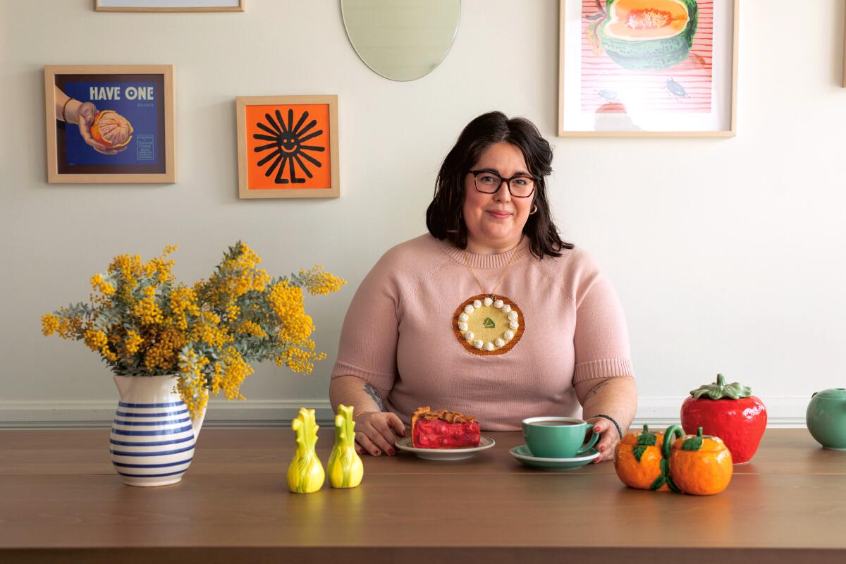 Nicole Rucker seated at a table. Before her are flowers, a slice of pie, a coffee and food-themed decorations.