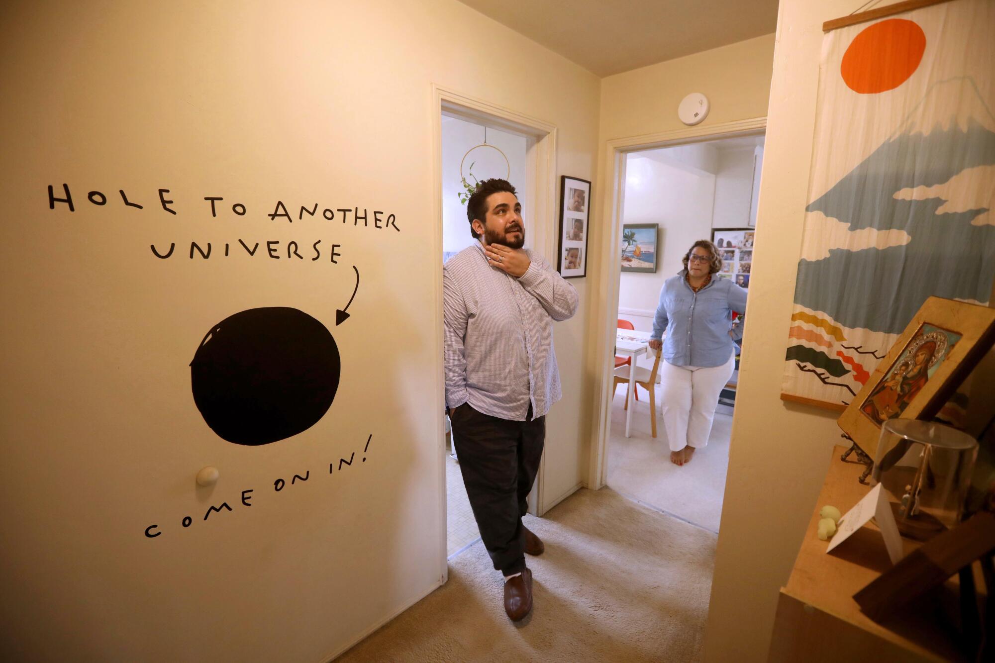 Abraham and Cecilia Beltran stand in the hallway of their apartment