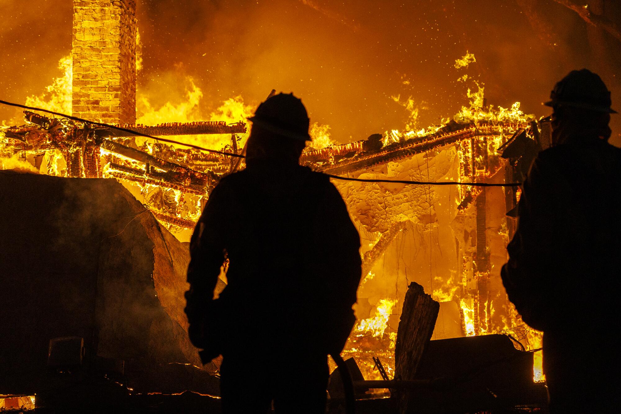 Firefighters work Jan. 8, 2025, to keep flames at an Altadena home from spreading to a nearby home during the Eaton fire