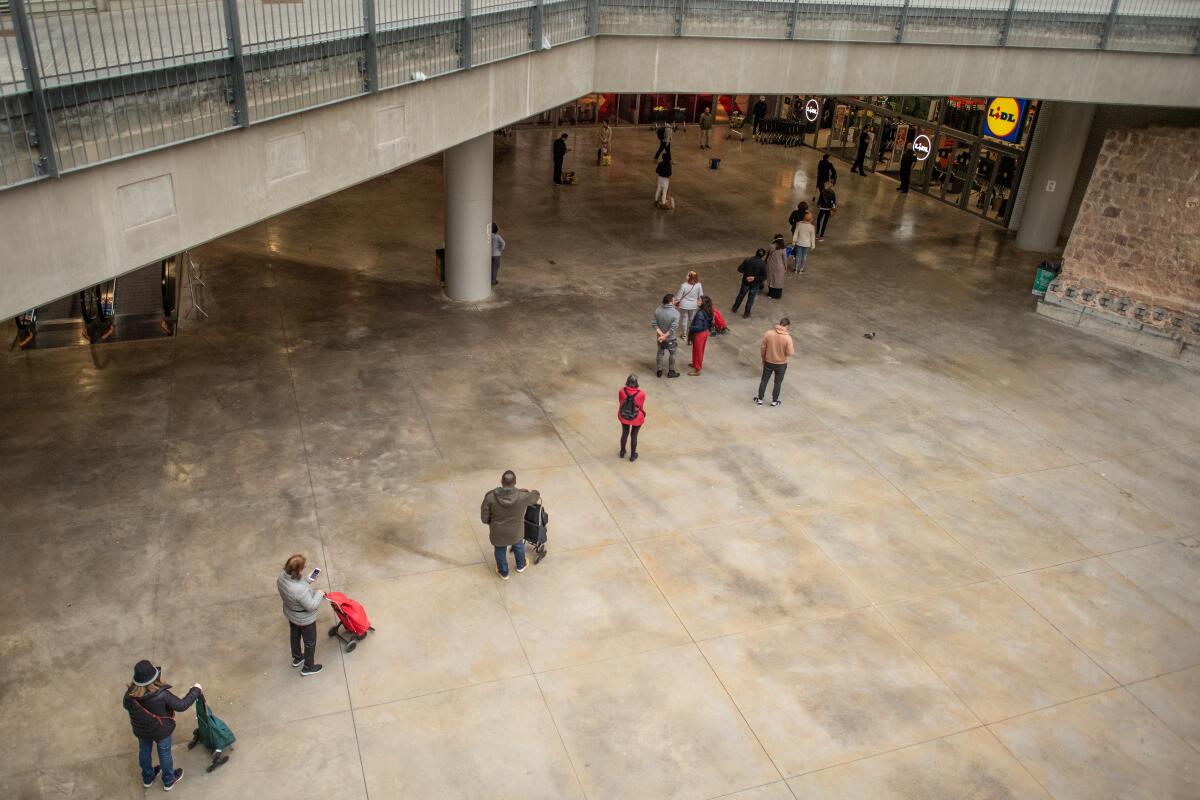 People keep their distance as they wait in line