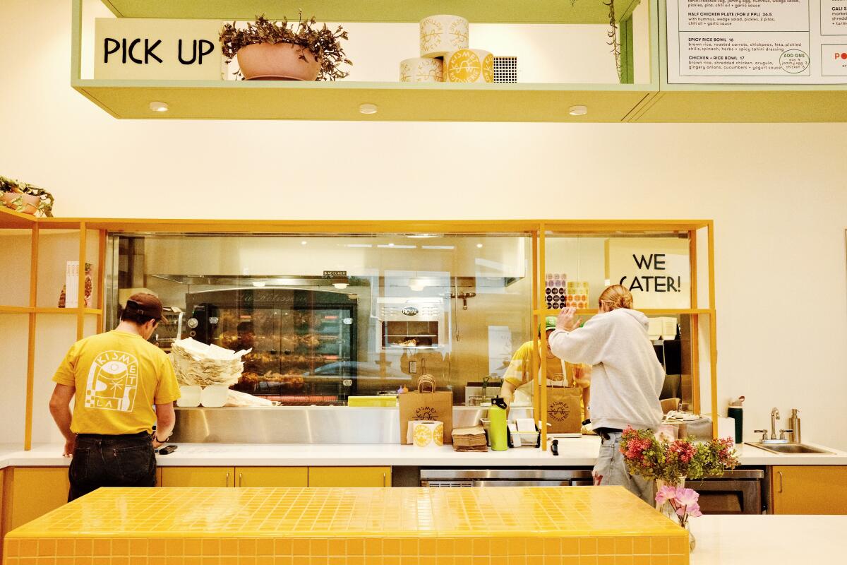 The front counter of Kismet Rotisserie in Pasadena. Roast chicken spins on a spit in the kitchen behind the counter.